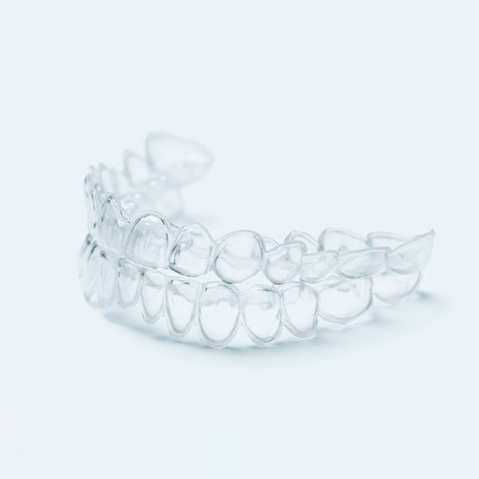 Clear professional teeth whitening trays with dosing dots on light blue background
