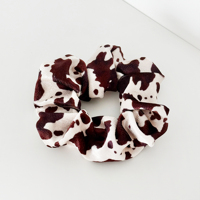 Brown-and-white cow print scrunchie with a bold pattern and soft fabric, by Coconut Lane.