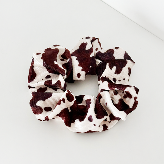 Brown-and-white cow print scrunchie with a bold pattern and soft fabric, by Coconut Lane.
