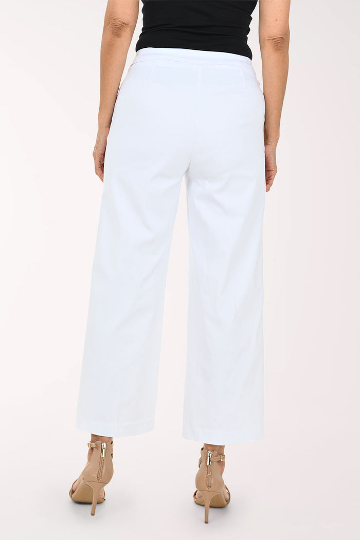 White cropped wide-leg pants with decorative gold-tone buttons on the sides, shown on a model wearing a black top and beige strappy heels against a light studio background.
