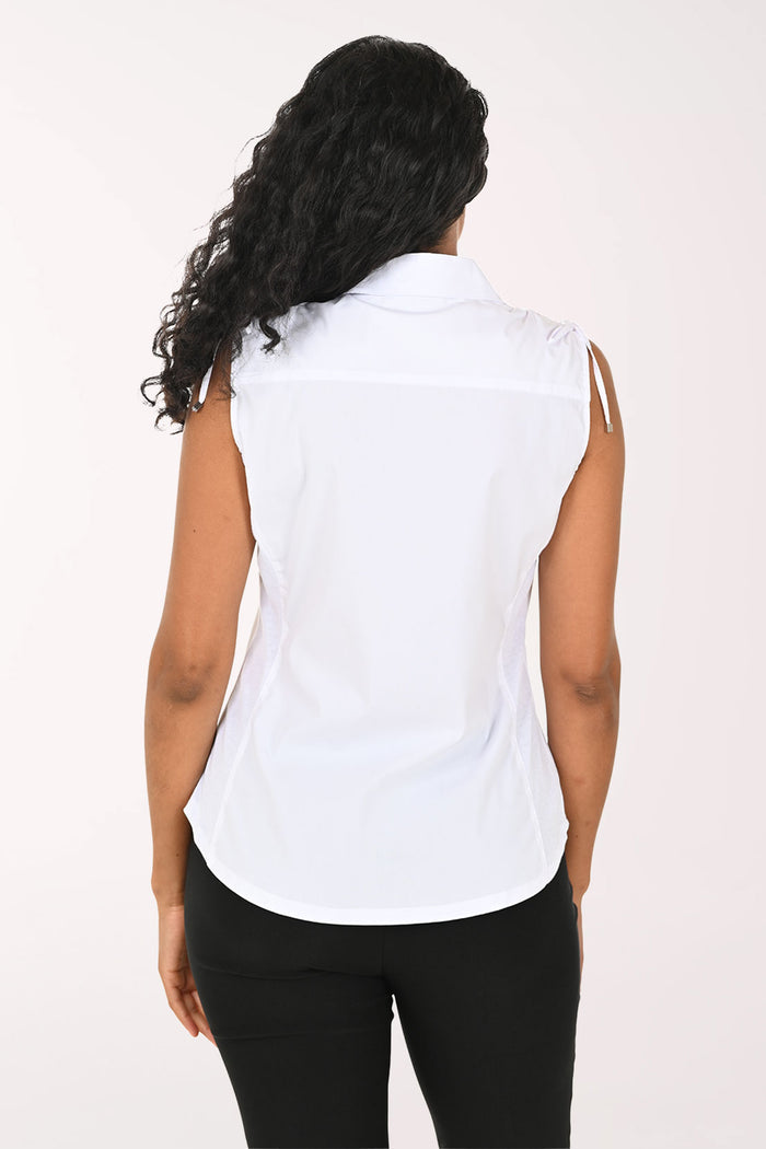 Woman wearing a sleeveless white blouse against a plain background