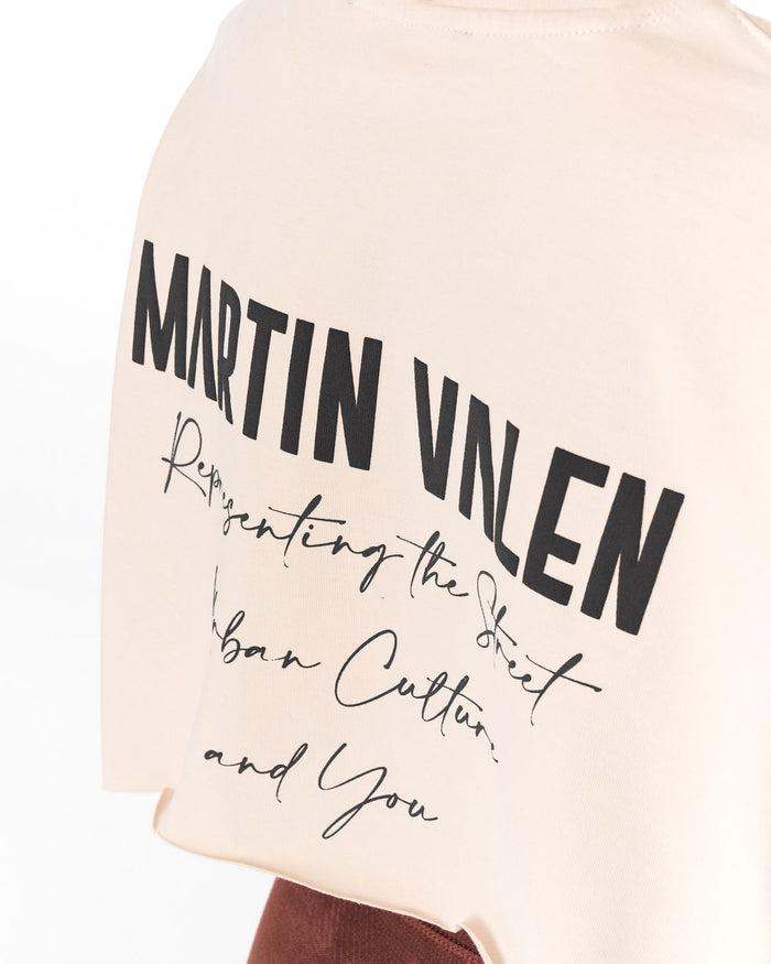 Close-up of a cream-colored t-shirt featuring bold black text that reads 'MARTIN VALEN' with cursive text underneath reading 'Representing the Street Urban Culture and You'.