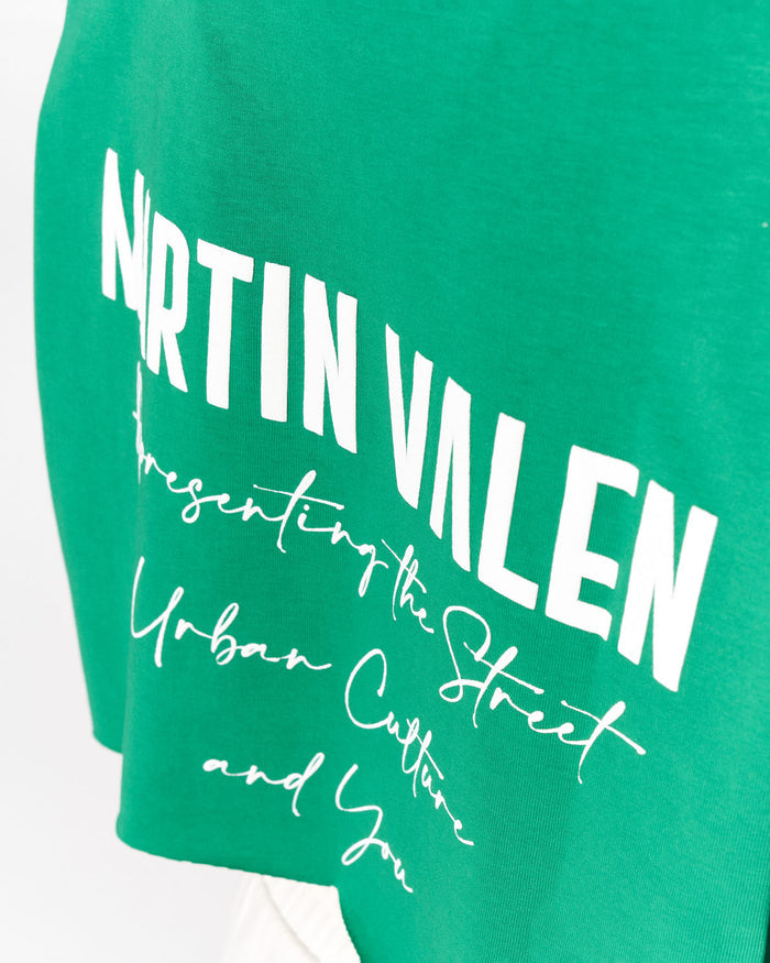 A close-up of a green t-shirt featuring a white graphic print that reads 'NRTIN VALEN' in bold block letters, followed by 'Presenting the Street Urban Culture and You' in a script font.