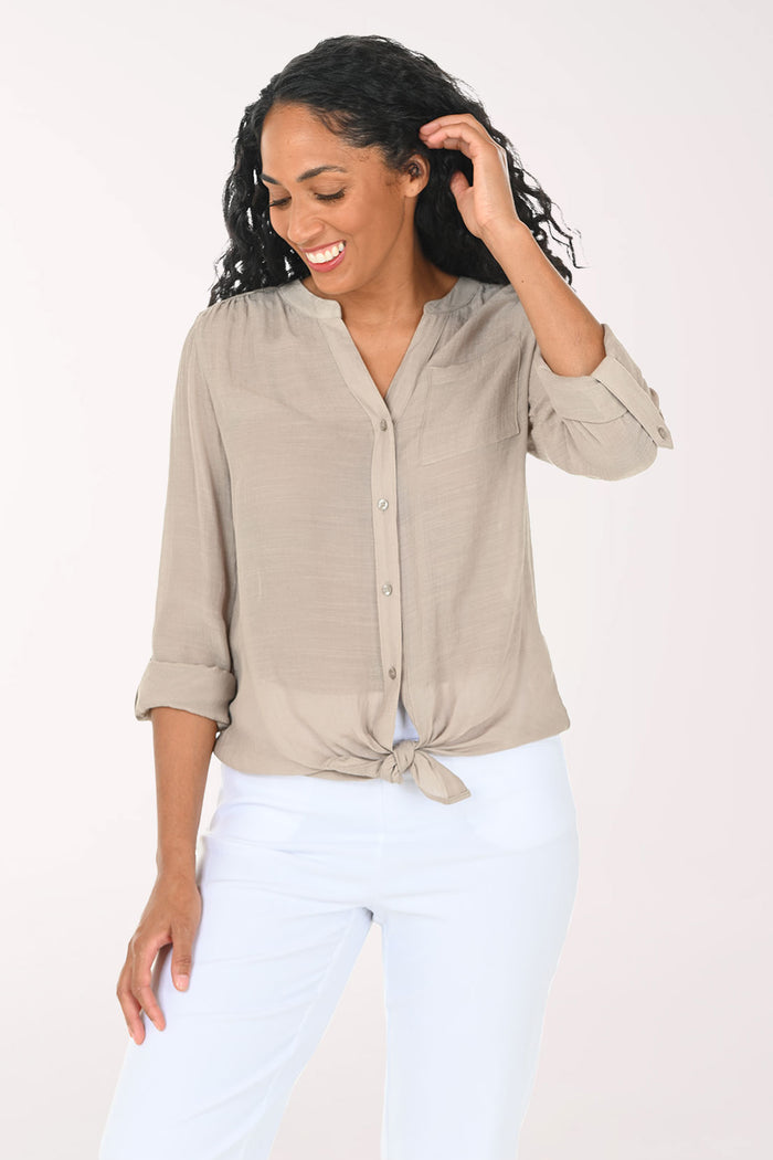 Woman wearing a beige button-up shirt with a white background