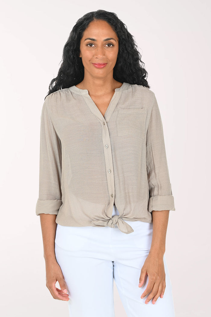 Woman wearing a beige button-up shirt with a white background