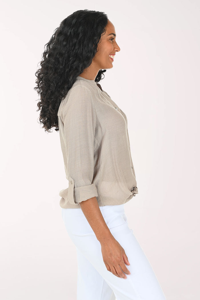 Woman wearing a beige button-up shirt with a white background