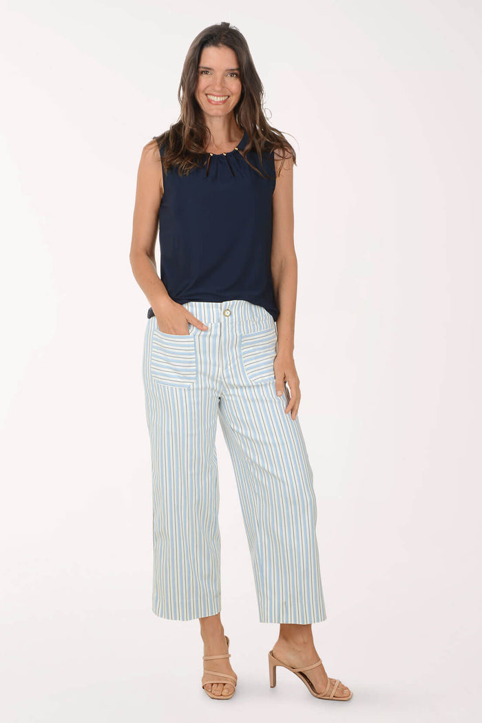 Woman wearing a navy sleeveless top and striped pants on a white background