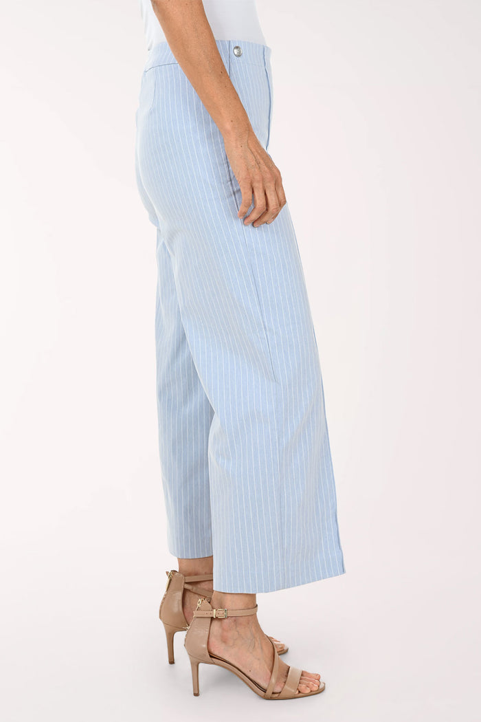 A model wearing light blue and white pinstriped cropped wide-leg pants with beige strappy heeled sandals, shown from the waist down against a plain white studio background.
