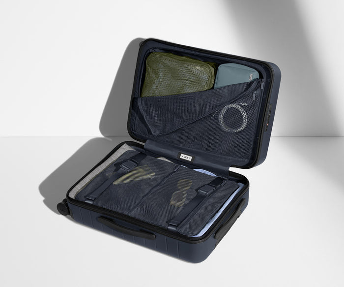 The Bigger Carry-On suitcase in Navy Blue shown open on its side and packed with Away's packing organizers to show capacity and the interior compression system, designed to help you pack more in
// 
Our signature interior compression system allows you to stay more organized. Paired with The Insider Packing Cubes.