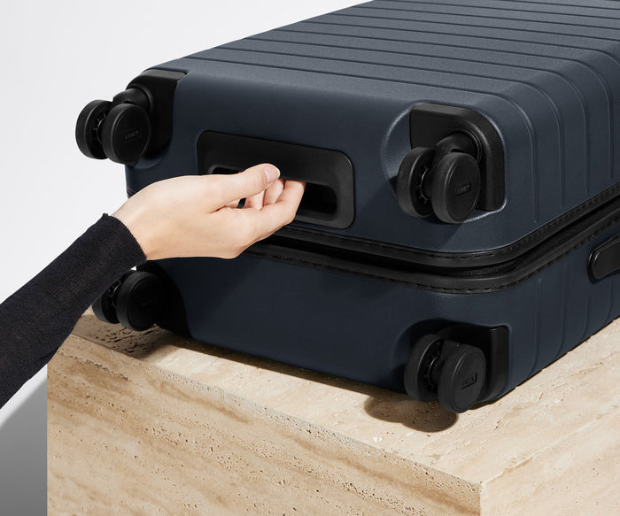 The Bigger Carry-On suitcase in Navy Blue shown from below highlighting the underside grab handle
// 
Underside grab handle that makes it easier to lift and carry your suitcase.