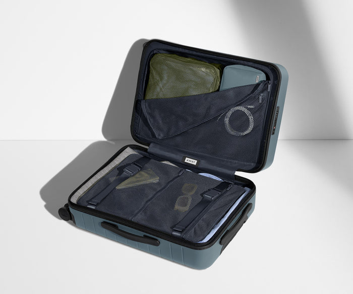 The Carry-On suitcase in Coast Blue shown open on its side and packed with Away's packing organizers to show capacity and the interior compression system, designed to help you pack more in
// 
Our signature interior compression system allows you to stay more organized. Paired with The Insider Packing Cubes.
