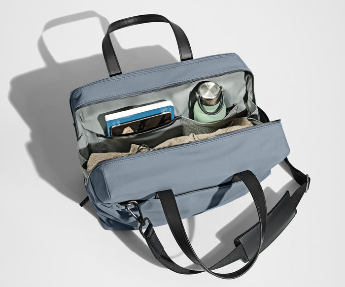 Main compartment packed with a light sweater, notebook, tablet, and water bottle. The detachable shoulder strap is clipped onto the bag.
// The Everywhere Bag features a detachable padded shoulder strap.
