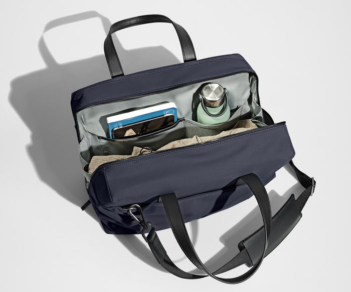 Main compartment packed with a light sweater, notebook, tablet, and water bottle. The detachable shoulder strap is clipped onto the bag.
// The Everywhere Bag features a detachable padded shoulder strap.