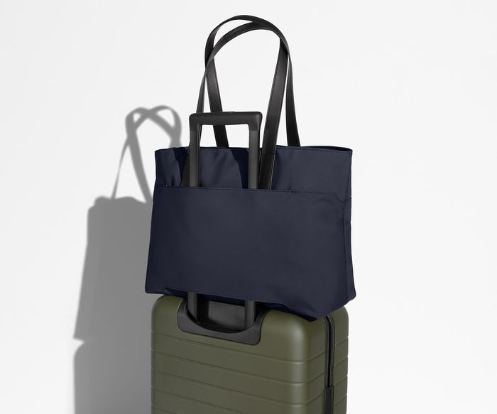 Everywhere Tote secured to an Away suitcase by its trolley sleeve