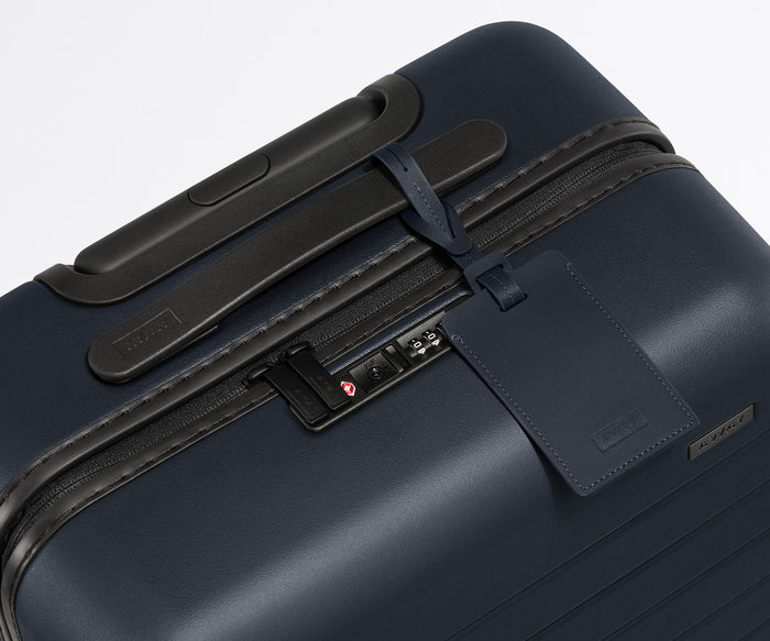 The leather luggage tag on top of a matching Away suitcase