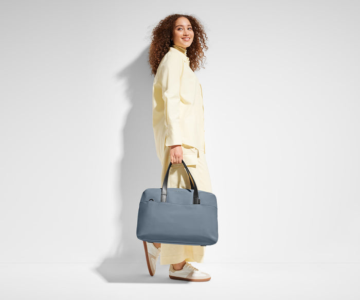 5'9" person carrying The Overnight Bag by its leather handles
// Model is 5’9”