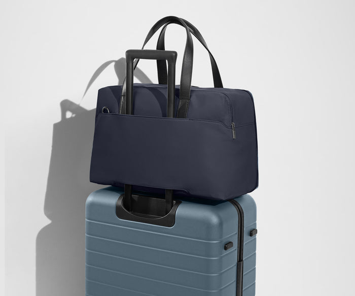 The Overnight Bag secured to an Away checked suitcase using the trolley sleeve
// Our duffles are designed with a trolley sleeve that slides onto your suitcase to keep it in place while you’re on the move. Paired with The Medium.