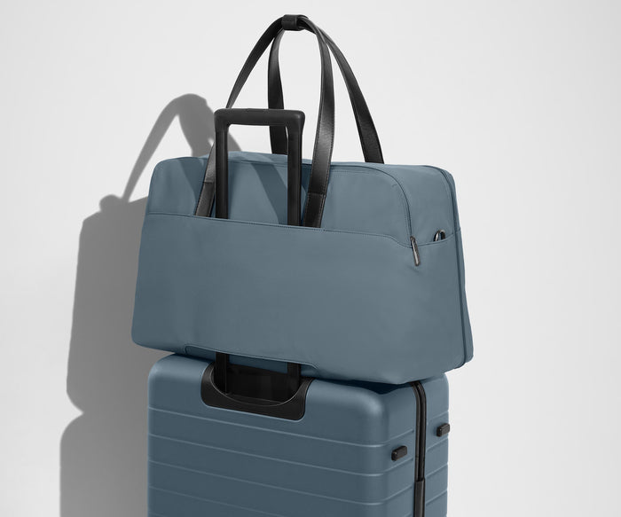 Weekender sitting on an Away Large suitcase, using the trolley sleeve pass-through
// Our duffles are designed with a trolley sleeve that slides onto your suitcase to keep it in place while you’re on the move. Paired with The Large.