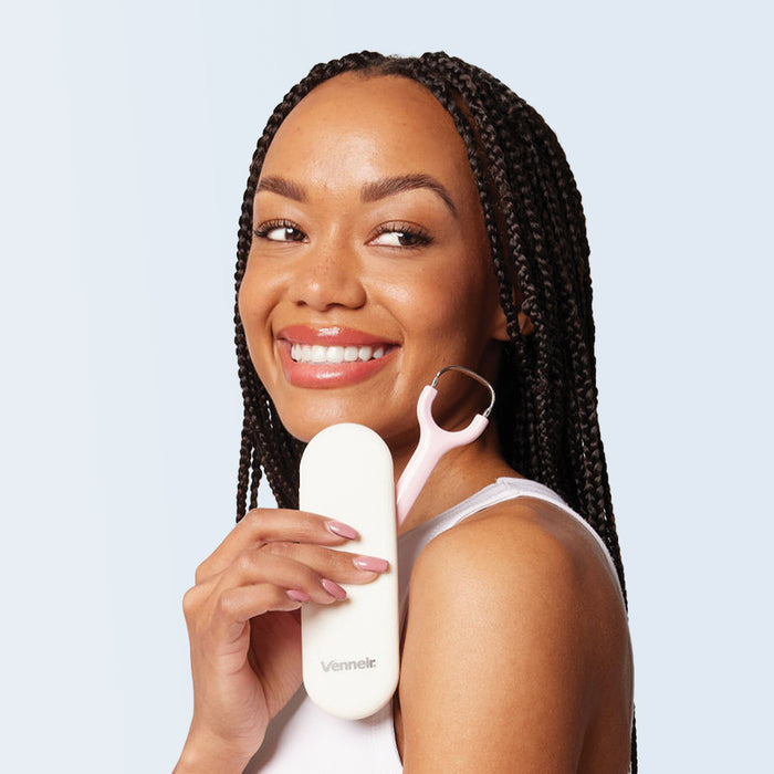 Woman holding stainless steel tongue scraper with pink handle