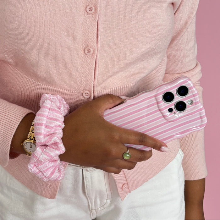 Person in a pink cardigan holds a pink striped phone case, wearing a Powder Stripes towel scrunchie.