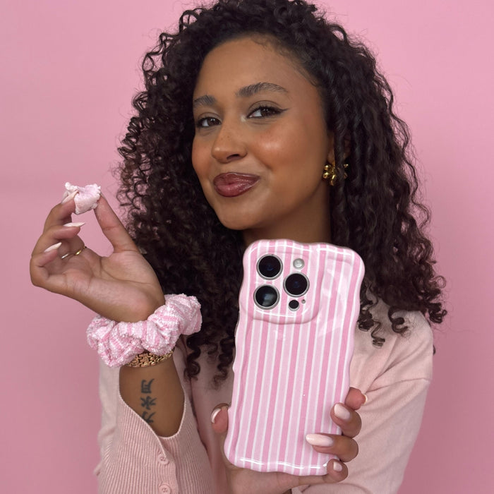 Woman with curly hair wearing a Powder Stripes TOWEL Scrunchie by Coconut Lane, holding a snack.